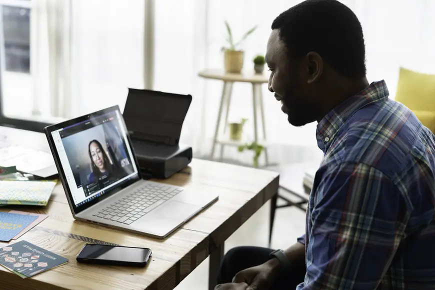 A man uses a laptop to have a Zoom video conference.
